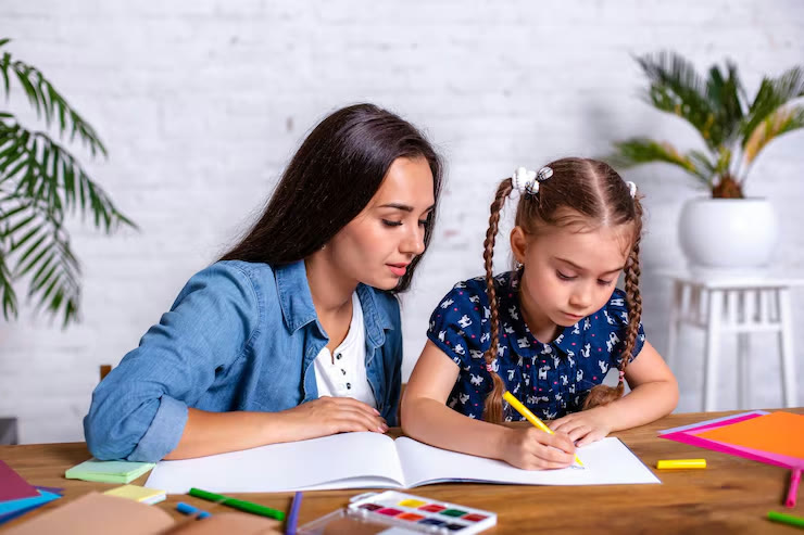 A mother sitting beside her daughter as she writes in an exercise book
